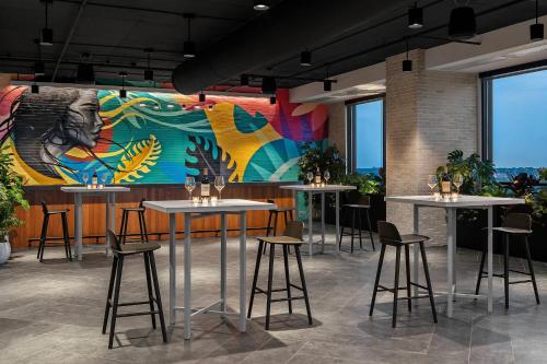 a restaurant with tables and chairs and a mural at Renaissance Milwaukee West Hotel in Wauwatosa