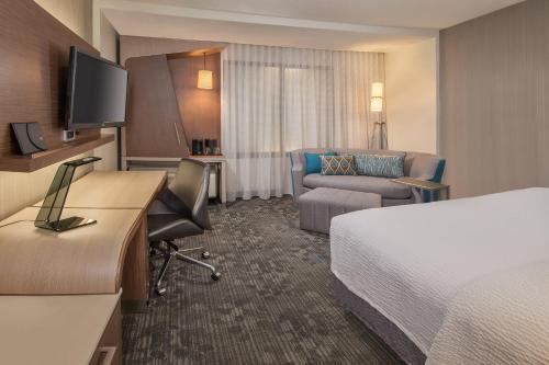 a hotel room with a bed and a desk and a couch at Courtyard by Marriott Mexicali in Mexicali