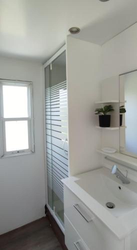 une salle de bain blanche avec un lavabo et une fenêtre dans l'établissement Bungalow au pied du Luberon, à Saint-Martin-de-la-Brasque