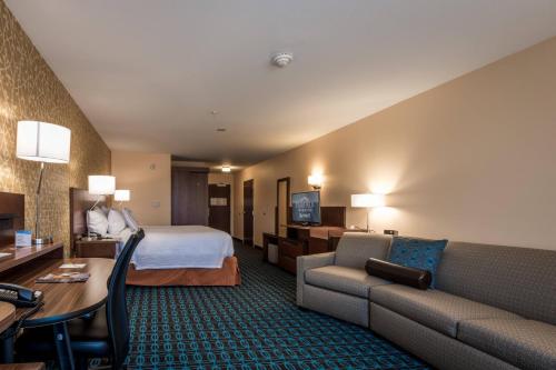 Fairfield Inn & Suites by Marriott Atmore في أتمور: غرفة في الفندق بها سرير وأريكة ومكتب