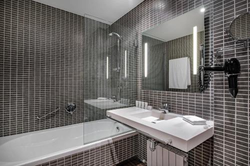 W łazience znajduje się umywalka, wanna i lustro. w obiekcie AC Hotel Burgos by Marriott w mieście Burgos