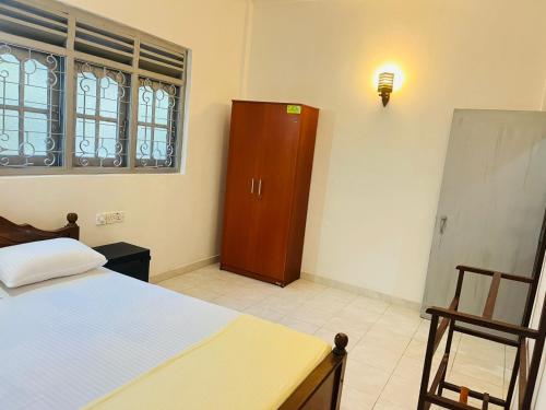 a bedroom with a bed and a wooden cabinet at Susha Happy One 2BR First Floor Apartment in Hikkaduwa