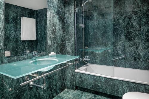 AC Hotel Ponferrada by Marriott في بونفيراذا: حمام مع حوض وحوض استحمام