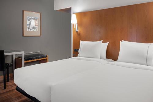 AC Hotel Ponferrada by Marriott في بونفيراذا: غرفة نوم مع سرير أبيض كبير ومكتب