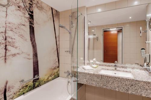 a bathroom with a tub and a sink and a shower at Courtyard by Marriott Zurich North in Zurich