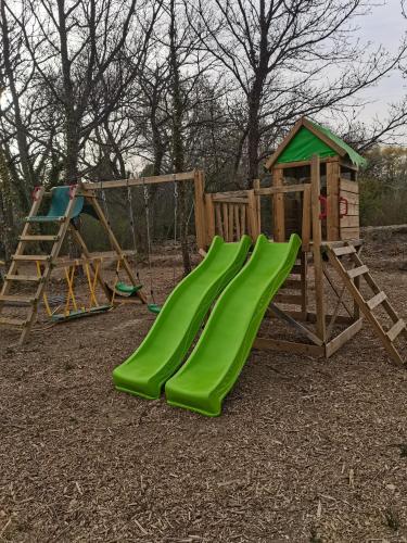 une aire de jeux en bois avec un toboggan vert et un jeu de jeux dans l'établissement Bungalow au pied du Luberon, à Saint-Martin-de-la-Brasque