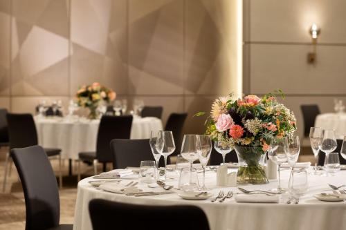 a table with glasses and a vase of flowers on it at The Westin London City in London