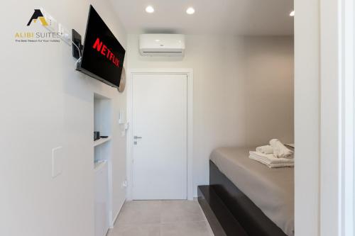 a bedroom with a bed and a tv on a wall at [ALIBI SUITES] Suite MUSEUM: Gioiello con Vista sul Museo Archeologico Nazionale, Letto e Doccia con Cromoterapia, Smart tv, WiFi e A/C in Ruvo di Puglia