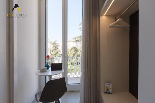 a room with a window with a table and a chair at [ALIBI SUITES] Suite MUSEUM: Gioiello con Vista sul Museo Archeologico Nazionale, Letto e Doccia con Cromoterapia, Smart tv, WiFi e A/C in Ruvo di Puglia