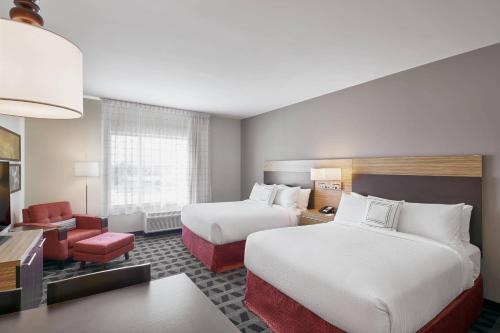 a hotel room with two beds and a chair at TownePlace Suites by Marriott Medicine Hat in Medicine Hat