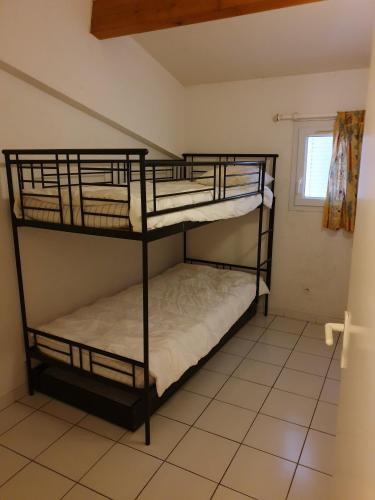 Cette petite chambre dispose de 2 lits superposés et d'une fenêtre. dans l'établissement ANDALOUSES Jolie villa T5 en duplex piscine proche plage Rochelongue Cap d'Agde, au Cap d'Agde