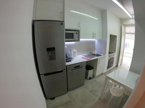 a kitchen with a stainless steel refrigerator and a table at Lisbon, renewed T1 apartment with pateo near Martires da Patria in Lisbon