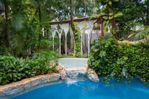 a swimming pool in the middle of a garden at Hotel Hulku in Playa del Carmen
