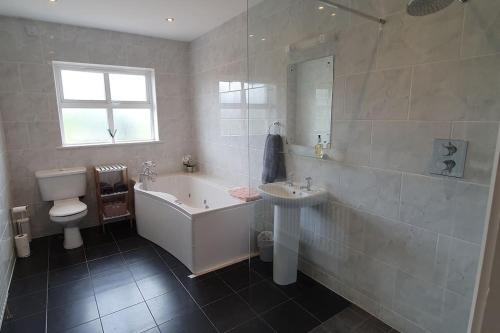 y baño con bañera, aseo y lavamanos. en Superb 4 Bed / 3 Bath Bungalow in Mitchelstown, en Mitchelstown