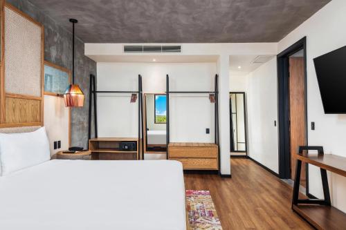 a bedroom with a bed and a desk in a room at Aloft Tulum in Tulum