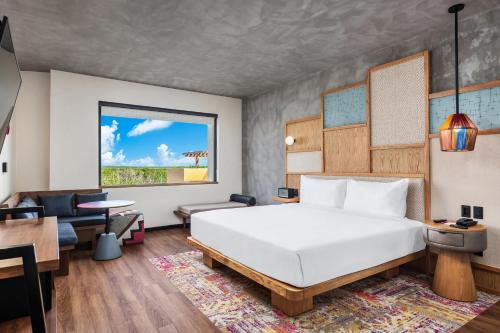 een hotelkamer met een bed, een bureau en een tafel bij Aloft Tulum in Tulum