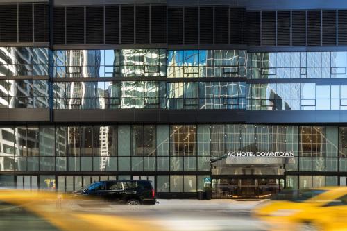 a large glass building with cars parked in front of it at AC Hotel by Marriott New York Downtown in New York