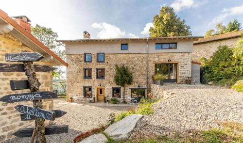 une maison en pierre avec un panneau devant elle dans l'établissement la source d'en haut, à Valcivières