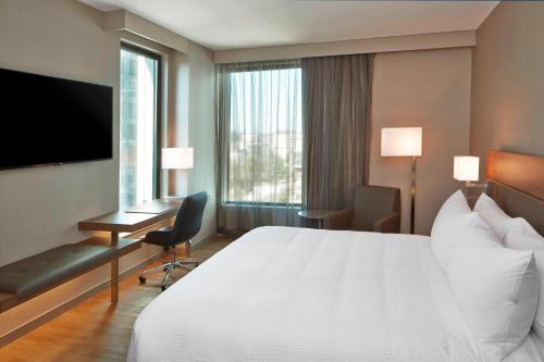 a hotel room with a bed and a desk and a television at AC Hotel by Marriott Seattle Bellevue/Downtown in Bellevue