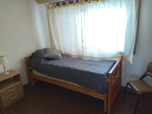 1 dormitorio con 1 cama con ventana y silla en San Martin & Salta en Mar del Plata