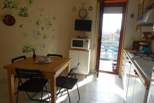 kuchnia ze stołem, krzesłami i kuchenką mikrofalową w obiekcie MomòHouse - 4 ospiti 2 camere WiFi A/C w Rzymie