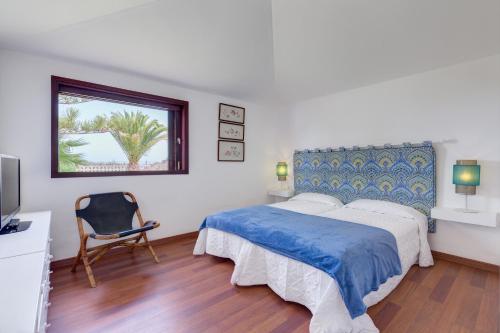 a bedroom with a bed and a chair and a window at Chalet Umbelina con jardin y vista al mar in Palm-mar