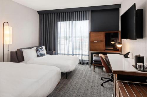 a hotel room with two beds and a desk at Courtyard by Marriott Owatonna Downtown in Owatonna