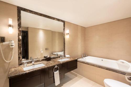 a bathroom with two sinks and a tub and a large mirror at Courtyard by Marriott Jazan in Jazan