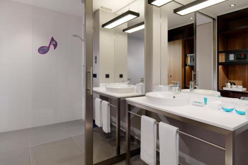 a bathroom with two sinks and two mirrors at Aloft München in Munich