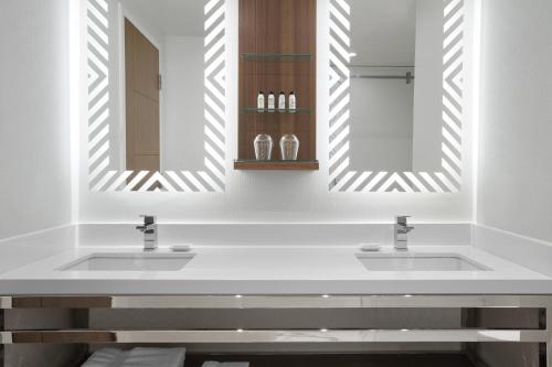 a bathroom with two sinks and two mirrors at Delta Hotels by Marriott Trois Rivieres Conference Centre in Trois-Rivières