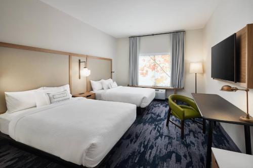 a hotel room with two beds and a desk and a television at Fairfield Inn & Suites by Marriott Raleigh Wake Forest in Wake Forest