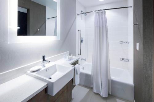 uma casa de banho branca com um lavatório e um chuveiro em SpringHill Suites by Marriott Clearwater Beach em Clearwater Beach