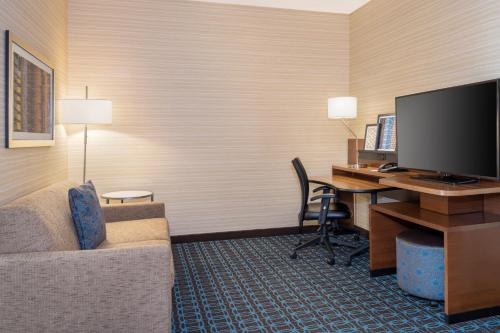a hotel room with a desk with a computer and a couch at Fairfield Inn & Suites by Marriott Los Angeles LAX/El Segundo in El Segundo