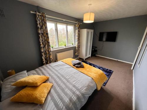 ein Schlafzimmer mit einem Bett mit gelber Bettwäsche und einem Fenster in der Unterkunft Spacious Apartment with Parking in Norwich
