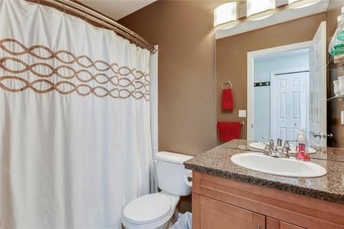 a bathroom with a toilet and a sink with a shower curtain at Stampede Park in Calgary