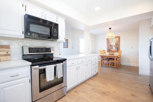 a kitchen with white cabinets and a black stove top oven at Las Palmas Retreat In Sunny St George with Pool in St. George