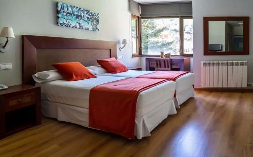 a bedroom with two beds with red pillows at Roca Blanca in Espot