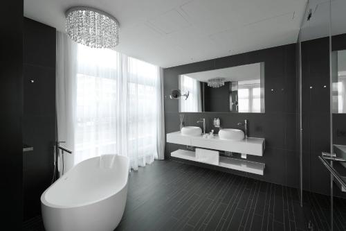 a bathroom with a tub and a sink and a mirror at Kameha Grand Zurich, Autograph Collection in Glattbrugg