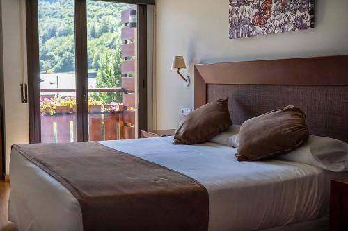 um quarto com uma cama com duas almofadas e uma janela em Roca Blanca em Espot