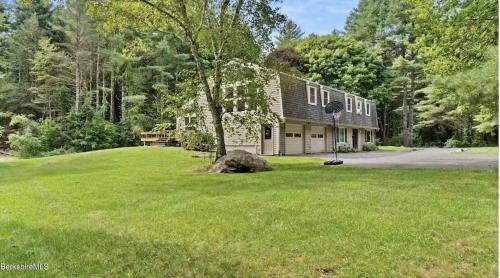 ein Haus inmitten eines Grasfeldes in der Unterkunft Woodland Hills Modern Cottage Minutes from Downtown Great Barrington in Great Barrington