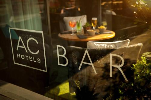a restaurant window with a table with glasses of wine at AC Hotel by Marriott Manchester Salford Quays in Manchester