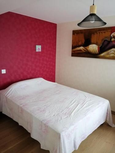 une chambre avec un lit blanc et un mur rouge dans l'établissement Charmante petite maison de vacances, à Saint-Clair-de-Halouze