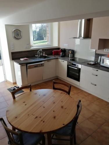 Il comprend une cuisine avec une table et des chaises en bois. dans l'établissement Charmante petite maison de vacances, à Saint-Clair-de-Halouze