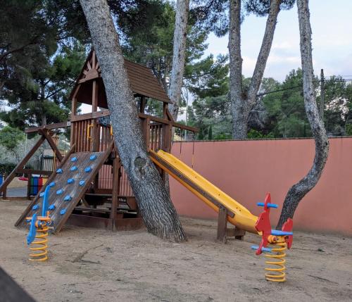 a playground with a slide and a tree at Hotel MR Les Rotes in Denia