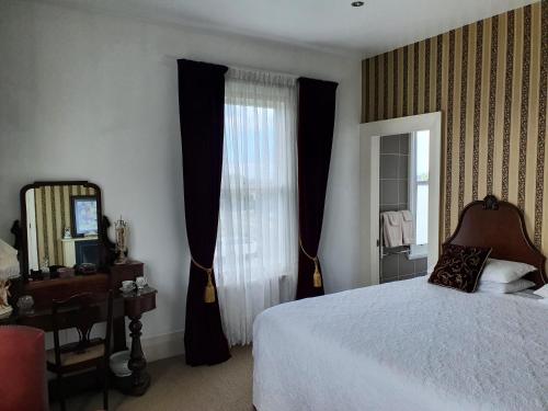 1 dormitorio con cama, espejo y ventana en Dalkeith Boutique Bed & Breakfast en Kaiapoi