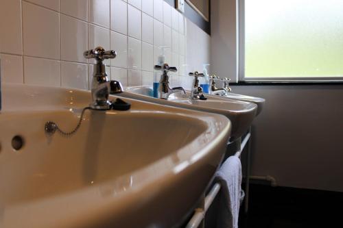 een wastafel in de badkamer met 2 kranen en een raam bij Ben Lettery Hostel in Ballynahinch