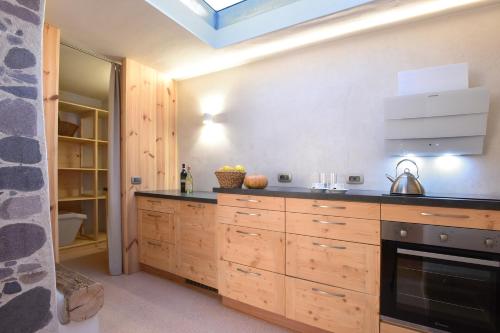 a kitchen with wooden cabinets and a stove at B&B Mas de Lagorae in Tesero