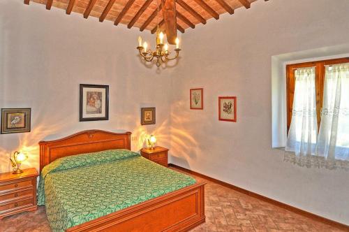 sypialnia z łóżkiem i żyrandolem w obiekcie Agriturismo Fattoria il Piano - Casa Bugno - San Gimignano w mieście San Gimignano