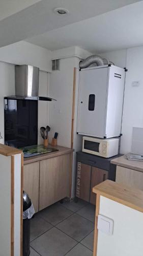 La cuisine est équipée d'un réfrigérateur blanc et d'un four micro-ondes. dans l'établissement Appartement entier Bourges Avaricum centre ville, à Bourges