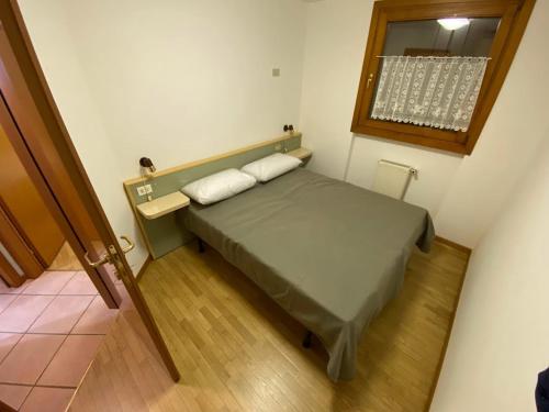 a small bedroom with a bed and a window at Lago 49 in Predazzo